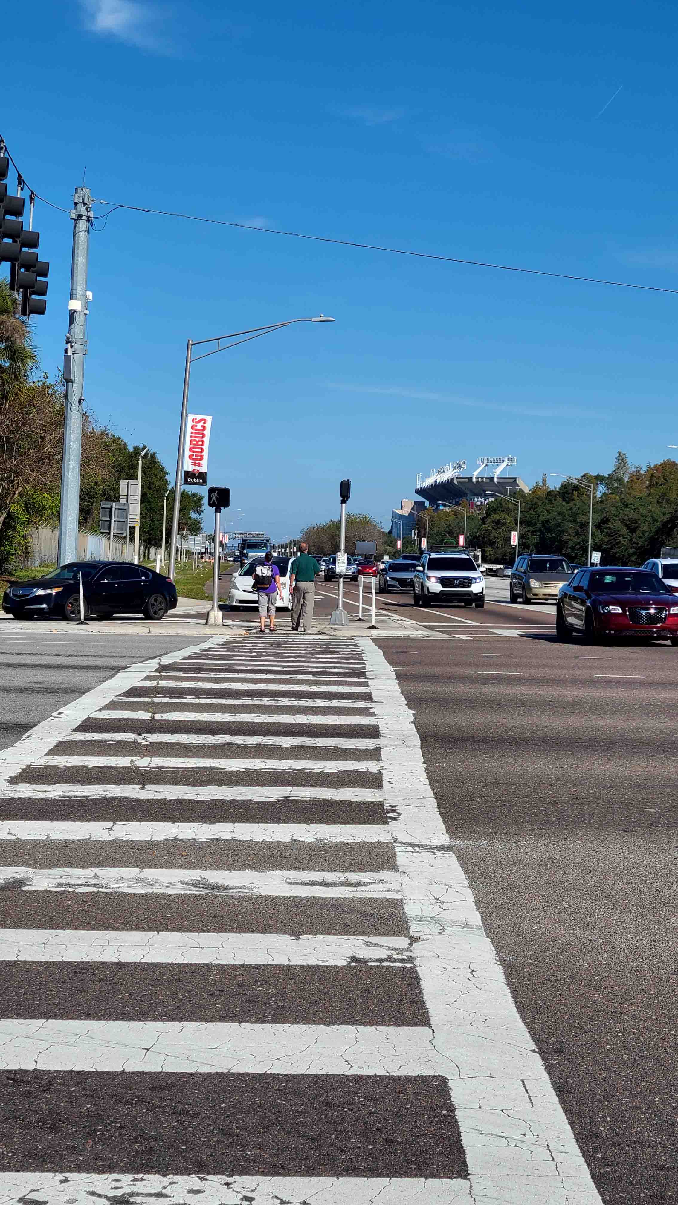 Image show a zebra-painted crosswalk crossing 9 lanes of traffic to reach and go through (at street-level) an island separating a right-turning lane.